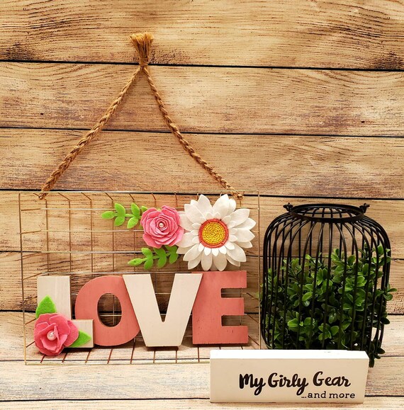 Love Sign felt flowers wall decor gold wire frame pink and white flowers and wood love in center hangs from braided twine