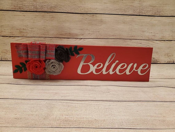 Painted red wood shelf sitting sign handmade felt flowers and with burlap and grey and red plaid bow and the metal cutout word Believe