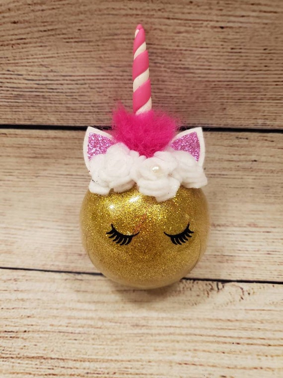 Gold glittery shatterproof unicorn ball ornament With a pink and white clay horn, faux leather ears and pink fur mane can be personalized.