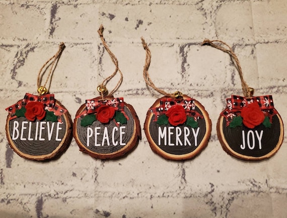 3 inch wood slice ornament set of 4. Painted black with Peace, Joy, Merry and Believe on them. With a felt flower, leaves, a bow, and twine.