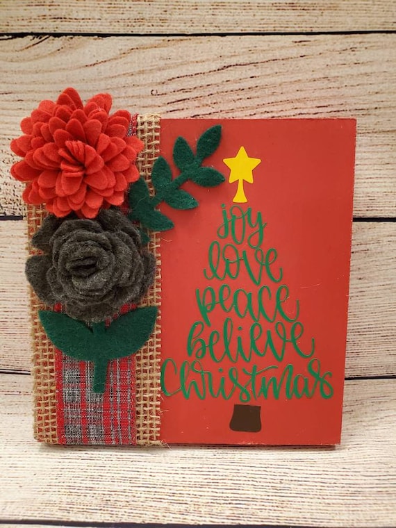 Wood holiday sign painted red with handmade felt flowers and leaves burlap and plaid ribbon and a Christmas tree word art in green