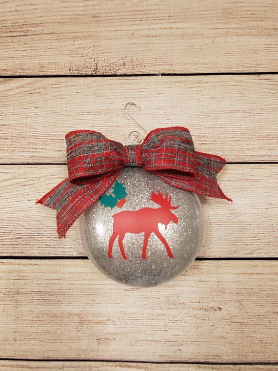 Large silver glittered disk ornament with a red and grey plaid bow and a red moose and holly on front Can be personalized with name and year