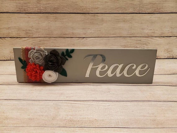 Grey painted wood shelf sitting sign with handmade felt flowers, burlap, plaid ribbon and a metal cutout of the word Peace