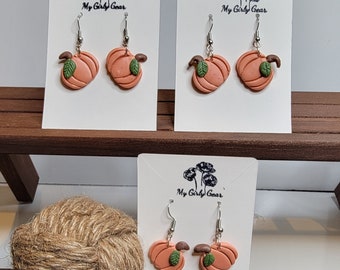 Cute pumpkin polymer clay handmade dangle  earrings with a green leaf and a brown stem. Perfect for Fall