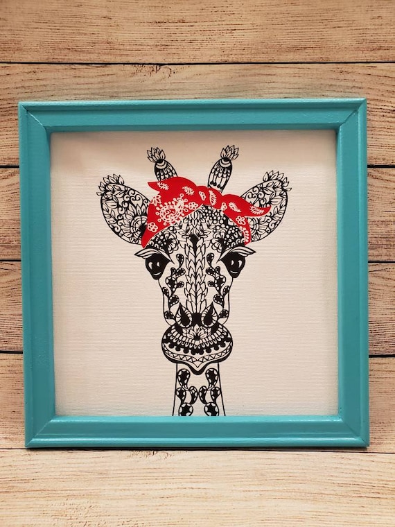 12×12in. Canvas with frame with a sassy giraffe mandala wearing a red bandana in a teal wood frame.