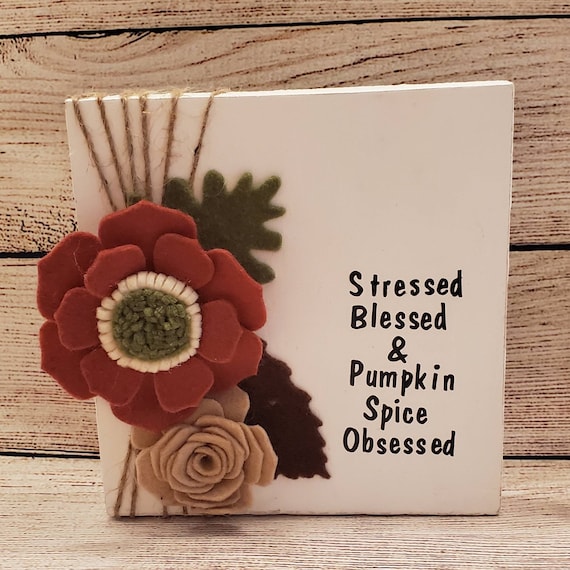 White Shelf/Desk sign Handmade felt flowers in rust with green center and a tan rose. The words Stressed Blessed and Pumpkin Spice Obsessed