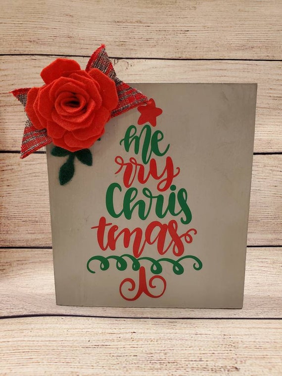Grey painted wood sign with handmade felt flower and leaves with small plaid bow and Christmas tree word art in red and green.