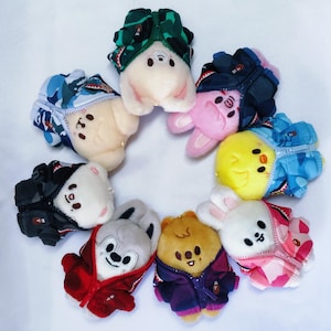 Puede incluir: Una colección de peluches de animales, cada uno con una chaqueta en miniatura con cremallera. Los animales de peluche incluyen un oso, un conejito y un pollito, en varios colores. Las chaquetas presentan patrones de camuflaje y otros.