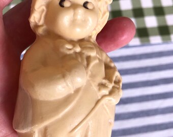 May include: A vintage cream-colored plastic doll with a bonnet and a dress. The doll is holding a small object in its hand.