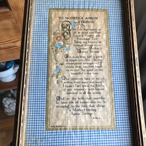 May include: A framed poem titled "To Mother's Apron Strings" with a blue and white gingham background. The poem is about the strength and importance of a mother's love.