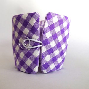 May include: A purple and white gingham fabric storage bin with a clear plastic button closure.