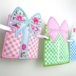 May include: A banner with four fabric squares, each with a different color and pattern. The squares are decorated with bows and the letters "LIL".