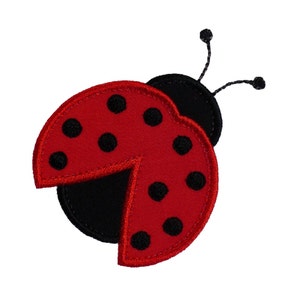 May include: A red ladybug with black spots and black legs, with its wings open. The ladybug is made of fabric and has a stitched outline.