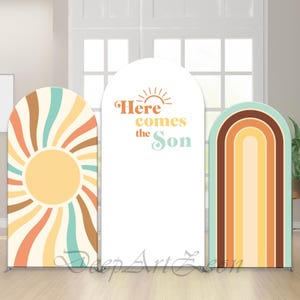 May include: Three arched backdrop panels with a retro design. The panels display a sunburst, the text "Here comes the Son", and a rainbow. The colour scheme includes orange, yellow, teal, and brown.