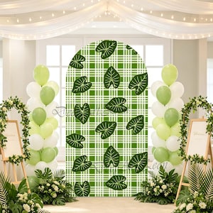 May include: An arched backdrop cover featuring a green and white plaid pattern decorated with scattered green leaf illustrations. The backdrop is flanked by two vertical balloon columns in shades of light green and white, with floral arrangements.