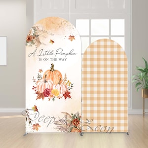 Könnte beinhalten: Ein herbstliches Hintergrundbild in Bogenform. Die linke Seite zeigt Kürbisse, Blumen und den Text "A Little Pumpkin Is On The Way". Die rechte Seite hat ein beige-weißes Vichy-Muster. Es wird von einem silbernen Metallrahmen getragen.