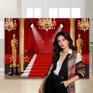 May include: A red carpet backdrop with a staircase, gold statues, and chandeliers. The backdrop features a red curtain, spotlights, and gold columns. A woman in a patterned jacket and black pants stands in front of the backdrop.