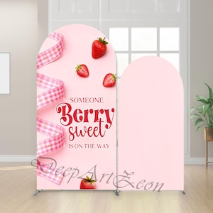 May include: A pink backdrop with an arch design, featuring the text "Someone Berry Sweet is on the Way." The design includes strawberries and a pink and white checkered ribbon. The backdrop is supported by a silver metal frame.
