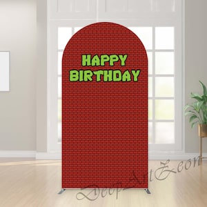 以下が含まれることがあります： アーチ型の赤いレンガ模様の背景。 「HAPPY BIRTHDAY」の文字は緑色で黒い縁取り。 背景は銀色の金属フレームで支えられており、誕生日のパーティーやイベントに最適です。