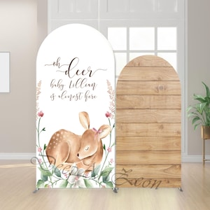 May include: A decorative arch backdrop for a baby shower. The left side features a watercolor illustration of a fawn with the text "oh deer baby Lillian is almost here". The right side has a wood-grain design.