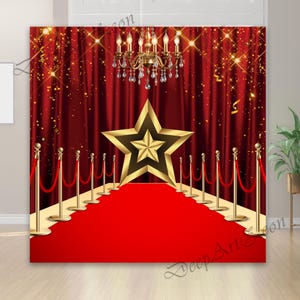 Puede incluir: Un telón de fondo de alfombra roja con una estrella dorada, cortinas de terciopelo rojo y una lámpara de araña dorada. Los postes dorados con cuerdas rojas bordean la alfombra. El telón de fondo está diseñado para un evento temático de Hollywood.