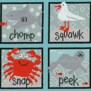 May include: A needlepoint artwork featuring four square panels with sea creatures. A gray shark with the word "chomp", a white seagull with "squawk", a red crab with "snap", and a gray seal with "peek".