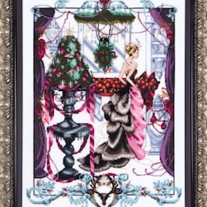 Może przedstawiać: Haft krzyżykowy w srebrnej ramie przedstawia kobietę w różowej i czarnej sukni w pobliżu udekorowanej choinki. Scena zawiera bogate detale architektoniczne, girlandy i dekoracyjną fontannę. Paleta kolorów obejmuje odcienie różu, czerni i koloru morskozielonego.