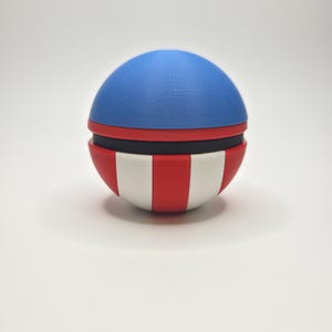 Peut inclure: Objet sph&eacute;rique avec un dessus bleu, une bande noire et un fond ray&eacute; rouge et blanc. L'objet est un &eacute;l&eacute;ment d&eacute;coratif, peut-&ecirc;tre un r&eacute;cipient ou un jouet, avec un code couleur patriotique.