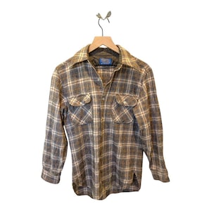 May include: A long-sleeved, button-down shirt with a plaid pattern in shades of grey, white, and tan. The shirt has two chest pockets and a collar. The shirt is hanging on a wooden hanger.