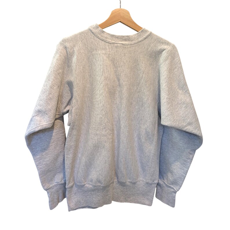 May include: A light gray sweatshirt with a crew neck and long sleeves, hanging on a wooden hanger. The sweatshirt has ribbed cuffs and hem. The fabric appears to be a soft, comfortable material.