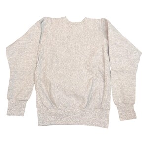 K&ouml;nnte beinhalten: Ein hellgraues Sweatshirt mit Rundhalsausschnitt und langen &Auml;rmeln. Das Sweatshirt hat gerippte B&uuml;ndchen und einen gerippten Saum. Der Stoff hat ein strukturiertes Aussehen. Das Kleidungsst&uuml;ck liegt flach auf wei&szlig;em Hintergrund.
