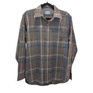 May include: A long-sleeved, button-down shirt in a plaid pattern of gray, blue, and orange. The shirt has a collared neckline and a single chest pocket. The fabric appears to be a wool blend. The shirt is hanging on a black hanger.