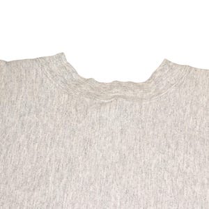 K&ouml;nnte beinhalten: Nahaufnahme eines melierten, grauen Sweatshirts mit Rundhalsausschnitt. Der Stoff hat ein strukturiertes Aussehen. Der Halsausschnitt ist sichtbar und zeigt die gerippten Kragendetails. Der Hintergrund ist schlicht wei&szlig;.