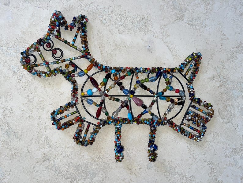 May include: A decorative dog sculpture crafted from beads and a black metal frame. The dog features a variety of colourful beads, including blue, green, red, and yellow. This handcrafted piece is designed for display.