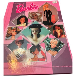 May include: A pink book titled "The Story of Barbie" with a collage of Barbie dolls. The cover features the title in a bubble-style font and a geometric design. The book showcases various Barbie dolls in different outfits and hairstyles.