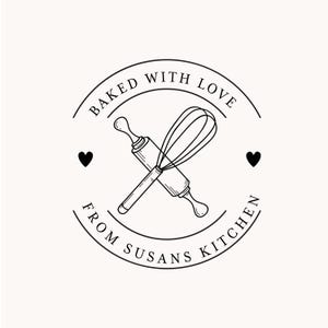 May include: Black and white logo with the text "Baked with Love from Susans Kitchen" in a circle. Inside the circle are crossed images of a rolling pin and a whisk. There are two hearts on either side of the circle.