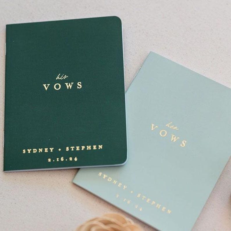 May include: Two rectangular vow booklets with gold foil lettering. The dark green booklet features the text his VOWS, SYDNEY + STEPHEN, and 2.16.24. The light sage green booklet features the text her VOWS, SYDNEY + STEPHEN, and 2.16.24.