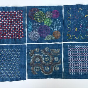 May include: Six denim squares with various colorful embroidered patterns. Designs include spirals, geometric shapes, and wavy lines, using red, blue, green, yellow, purple, and brown thread. The squares are arranged in a grid.