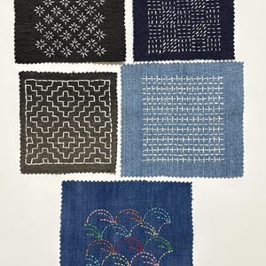 Puede incluir: Cinco muestras de tela cuadradas con diseños bordados. La muestra superior izquierda es negra con patrones de estrellas blancas. La superior derecha es azul marino con costuras lineales blancas. La inferior izquierda es gris oscuro con formas geométricas blancas. La inferior derecha es azul claro con costuras de rejilla blancas. La muestra inferior es azul marino con costuras arqueadas coloridas.