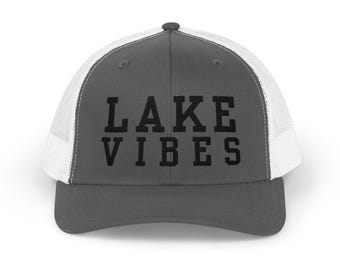 May include: A gray and white trucker hat with the text "LAKE VIBES" in black.