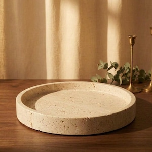 Travertine tray styled on wood table in warm light beside brass candlesticks and eucalyptus