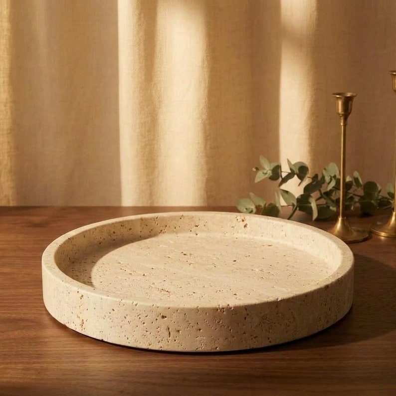 Travertine tray styled on wood table in warm light beside brass candlesticks and eucalyptus