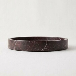 Side profile of round burgundy marble tray on white background