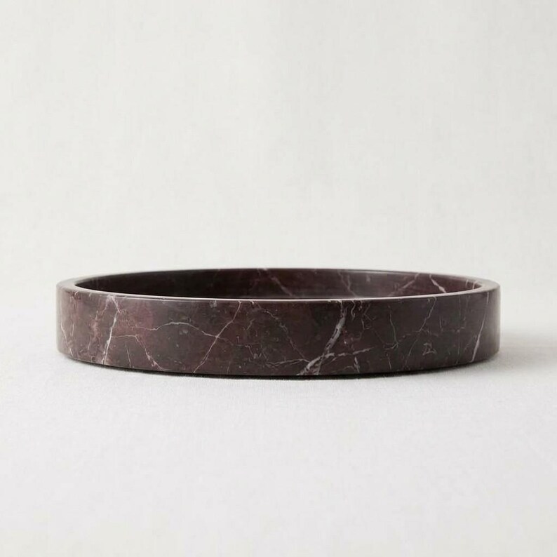 Side profile of round burgundy marble tray on white background
