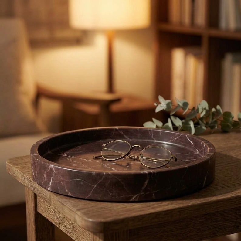 Rosso levanto marble tray styled on side table holding eyeglasses in warm lamp light