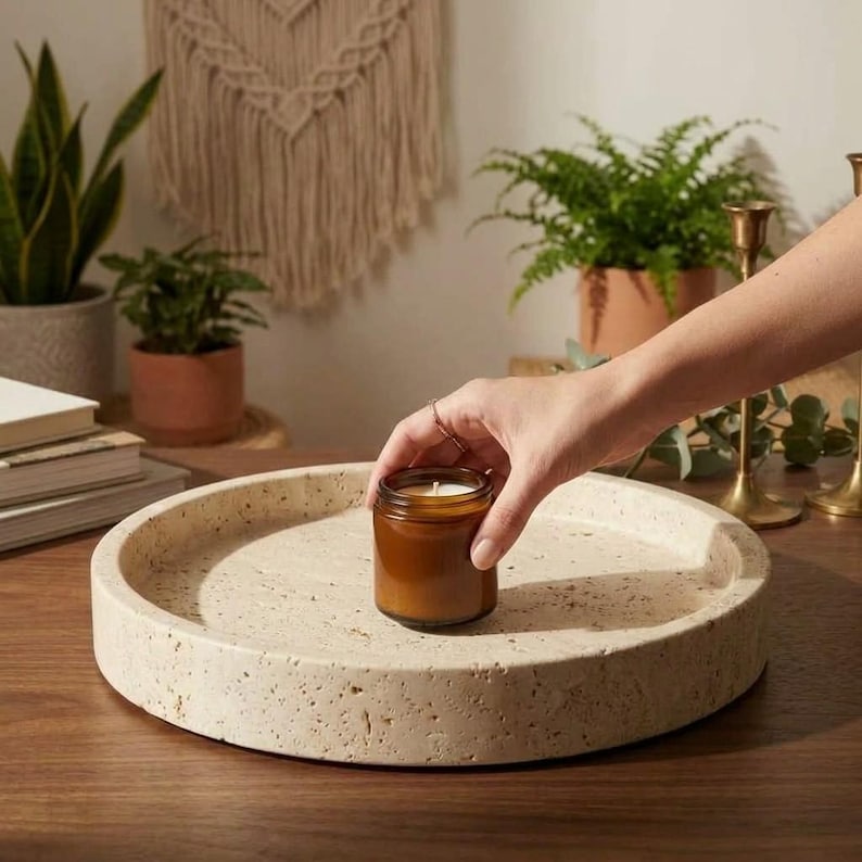 Travertine catchall tray styled on wood table holding a candle, with plants and books
