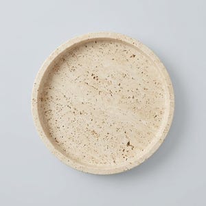 Overhead flat lay of round travertine tray showing natural pitted texture
