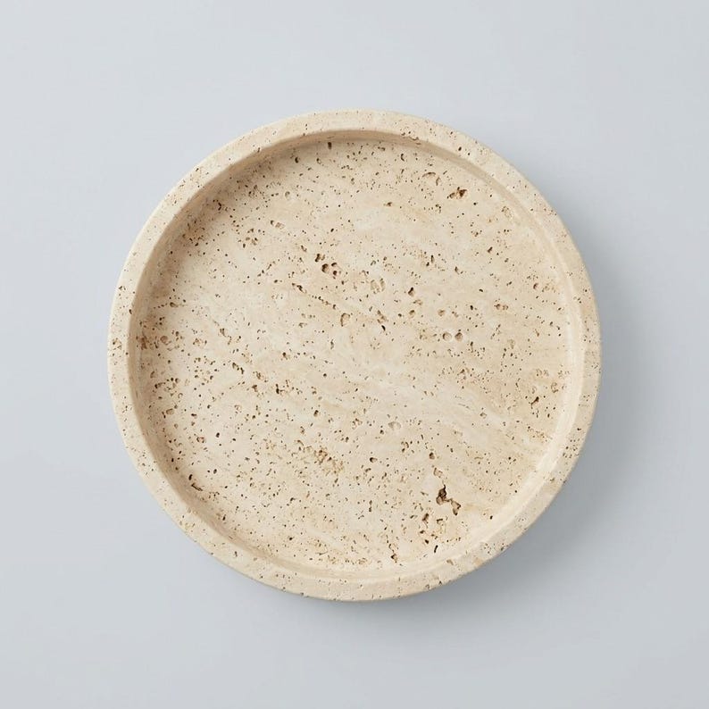 Overhead flat lay of round travertine tray showing natural pitted texture