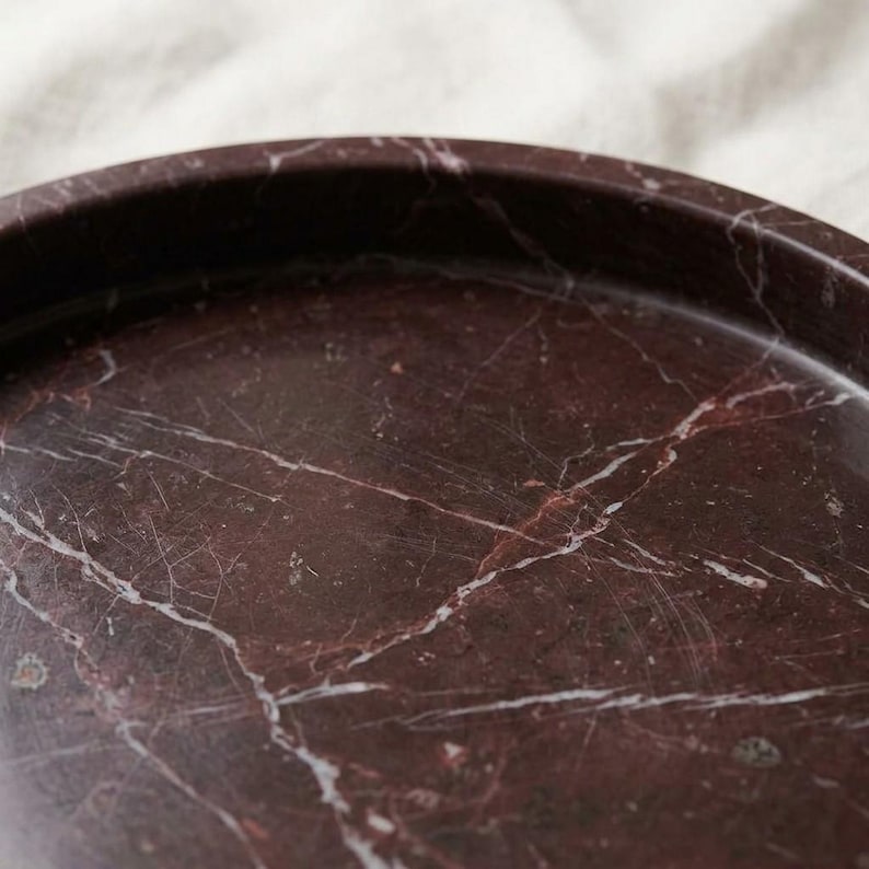 Close-up detail of rosso levanto marble tray surface showing dramatic white veining