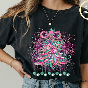 Puede incluir: Camiseta negra con un diseño colorido de árbol de Navidad. El árbol está adornado con una estrella rosa, un lazo y adornos colgantes. El diseño incluye salpicaduras de rosa, turquesa y morado, con las palabras "Digital Download".